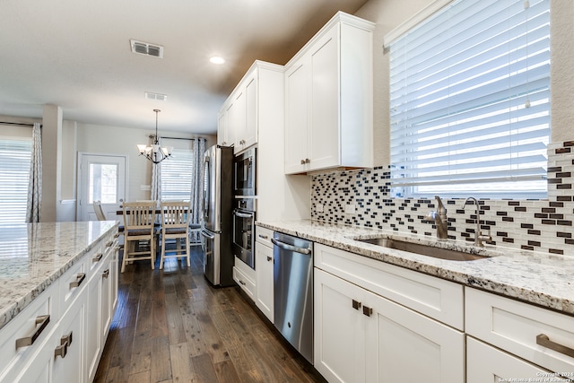 kitchen with a sink, visible vents, white cabinets, appliances with stainless steel finishes, and backsplash