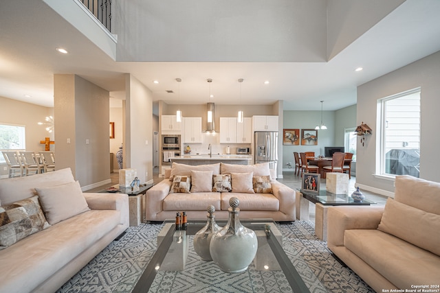 living room with a high ceiling, a chandelier, light hardwood / wood-style floors, and sink