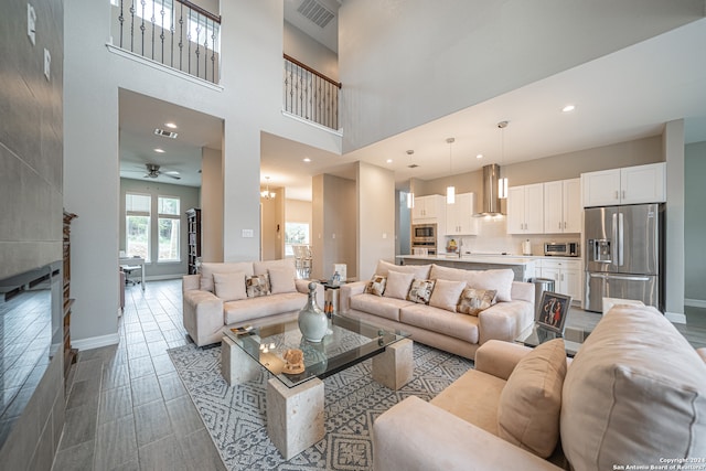 tiled living room with ceiling fan and a high ceiling