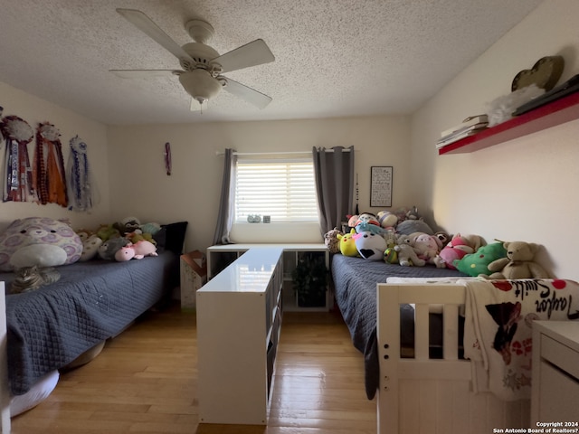 bedroom with light wood-type flooring, ceiling fan, and a textured ceiling