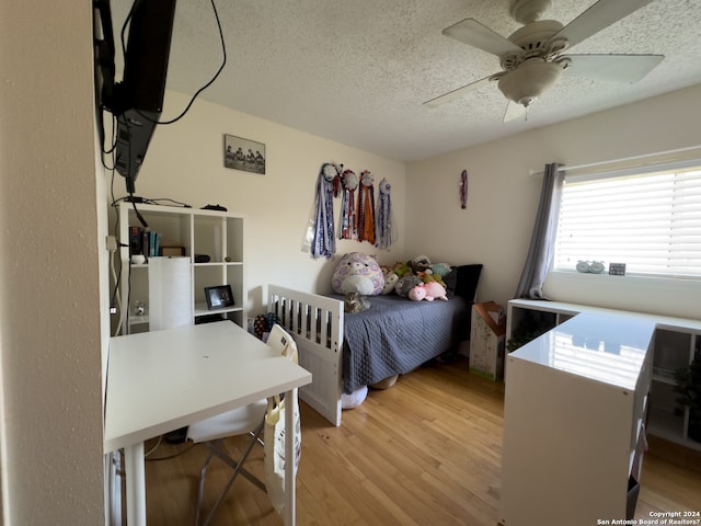 bedroom featuring ceiling fan, a textured ceiling, and light hardwood / wood-style floors