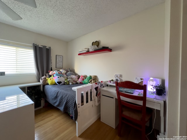 bedroom with light hardwood / wood-style flooring, ceiling fan, and a textured ceiling