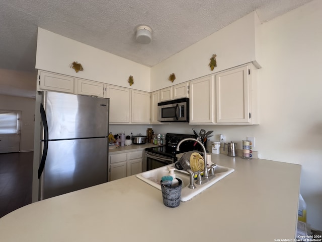 kitchen with white cabinets, a textured ceiling, appliances with stainless steel finishes, and kitchen peninsula