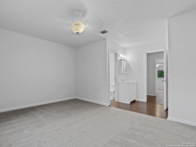 unfurnished room with dark carpet, ceiling fan, and a textured ceiling