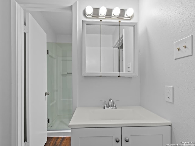 bathroom with hardwood / wood-style floors, a shower with shower door, and vanity