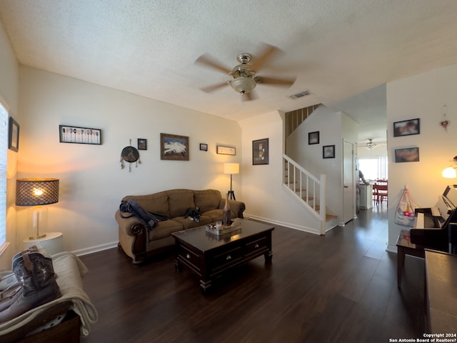 living room with ceiling fan, dark wood-type flooring, and a textured ceiling