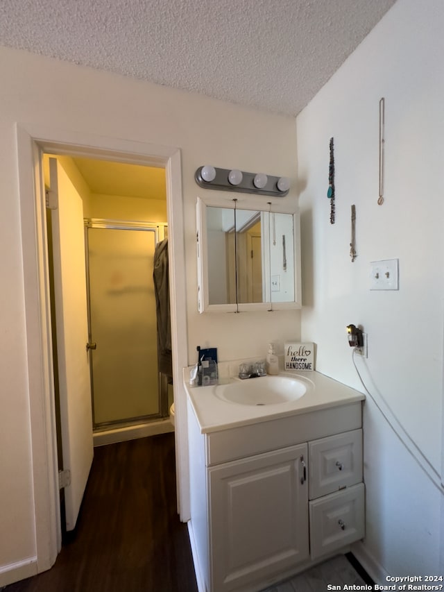 bathroom featuring vanity, a textured ceiling, wood-type flooring, a shower with door, and toilet