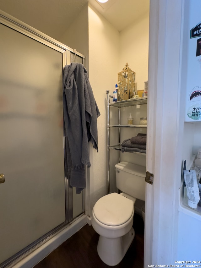 bathroom featuring wood-type flooring, toilet, and a shower with door