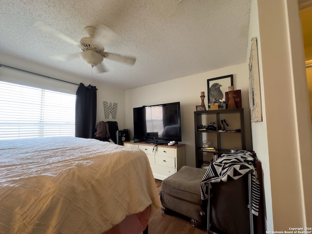 bedroom featuring ceiling fan, hardwood / wood-style flooring, a textured ceiling, and multiple windows