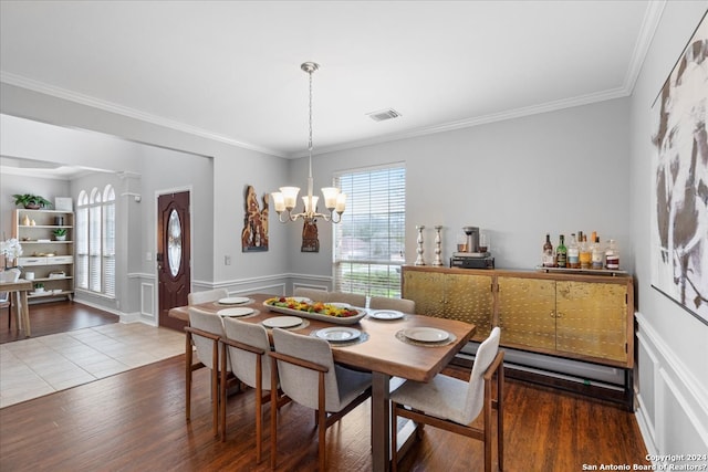 tiled dining space with an inviting chandelier and ornamental molding