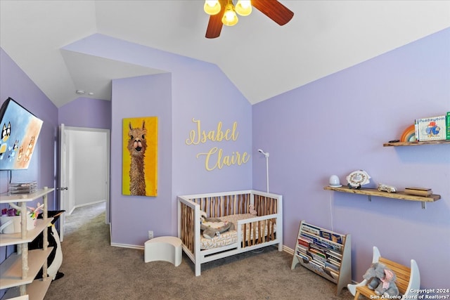 bedroom with lofted ceiling, ceiling fan, a crib, and dark colored carpet