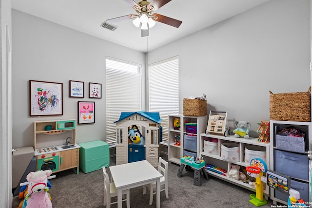 game room with ceiling fan and dark colored carpet