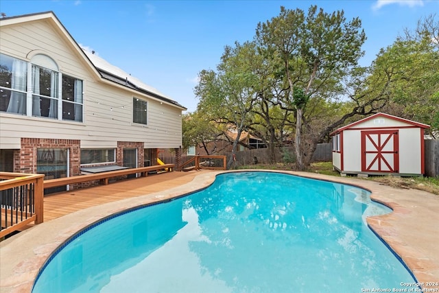 view of pool with a wooden deck and a storage unit