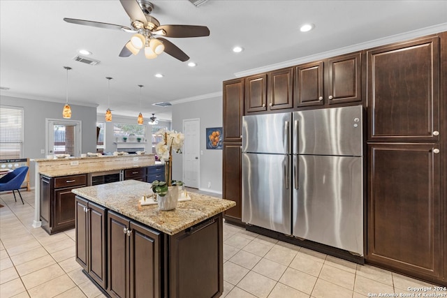 kitchen featuring decorative light fixtures, a center island, ceiling fan, stainless steel refrigerator, and light stone counters