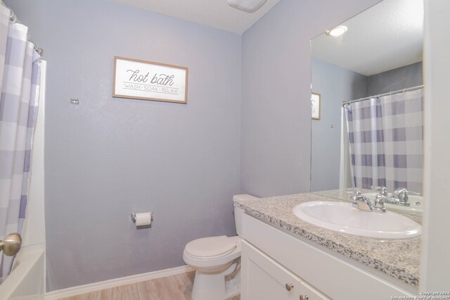 full bathroom featuring toilet, vanity with extensive cabinet space, shower / tub combo with curtain, and hardwood / wood-style flooring