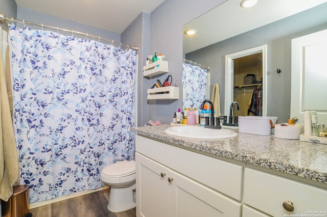 bathroom featuring wood-type flooring, toilet, and vanity with extensive cabinet space