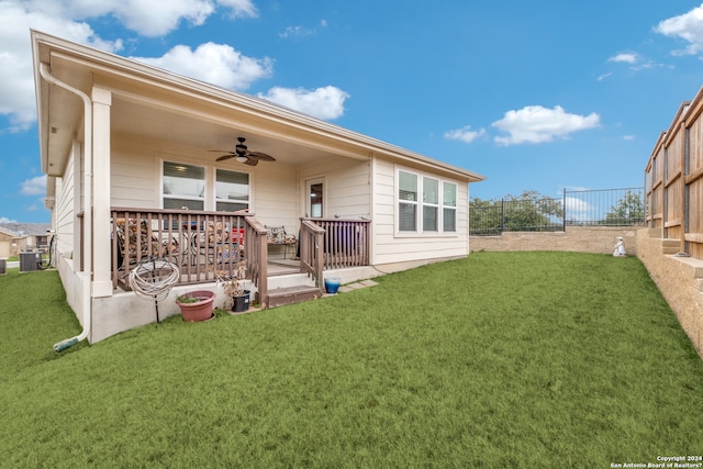 back of house featuring central AC, ceiling fan, and a yard