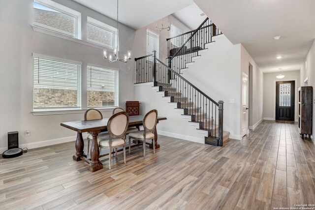 dining room featuring an inviting chandelier, a towering ceiling, and light hardwood / wood-style floors