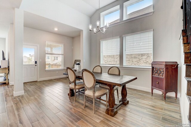 dining area featuring high vaulted ceiling, light hardwood / wood-style floors, and a chandelier