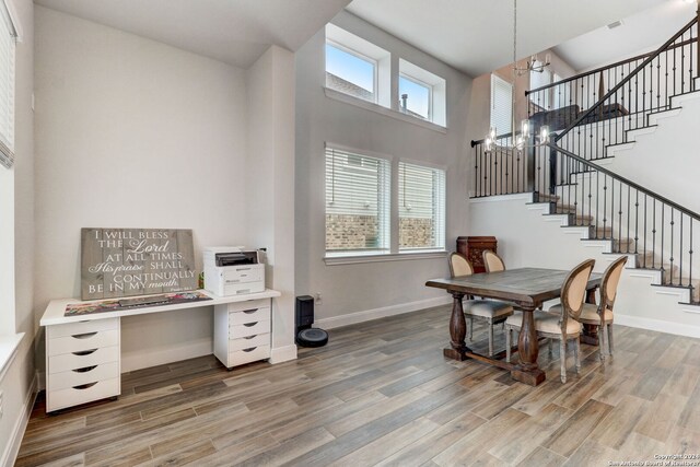 dining room with an inviting chandelier, a high ceiling, and hardwood / wood-style flooring