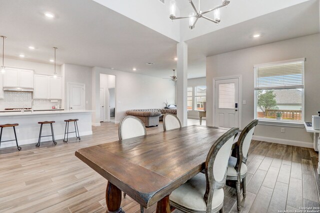 dining space featuring ceiling fan with notable chandelier and light hardwood / wood-style flooring