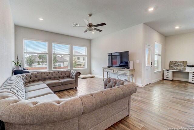 living room with ceiling fan, light wood-type flooring, and a wealth of natural light