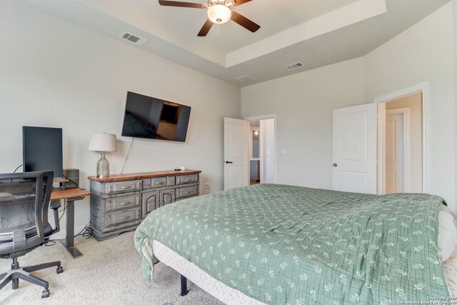 bedroom featuring ceiling fan, light colored carpet, and a tray ceiling