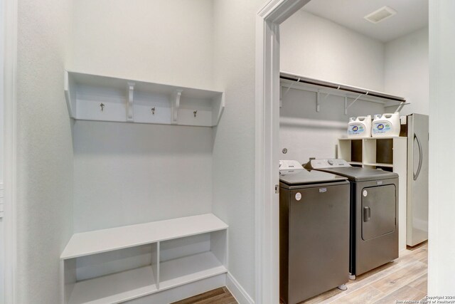 laundry room with washing machine and dryer and light hardwood / wood-style flooring