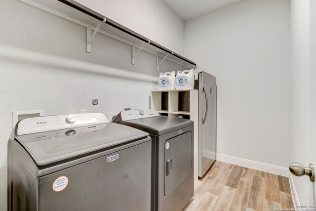 laundry area with separate washer and dryer and light hardwood / wood-style floors