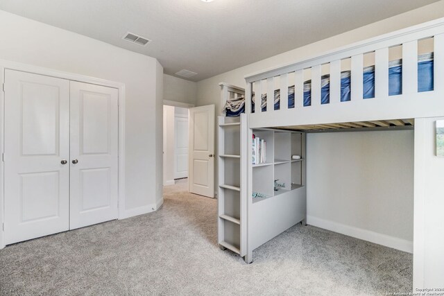 unfurnished bedroom with light carpet and a closet