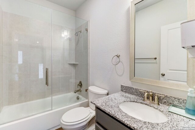 full bathroom with shower / bath combination with glass door, toilet, and vanity