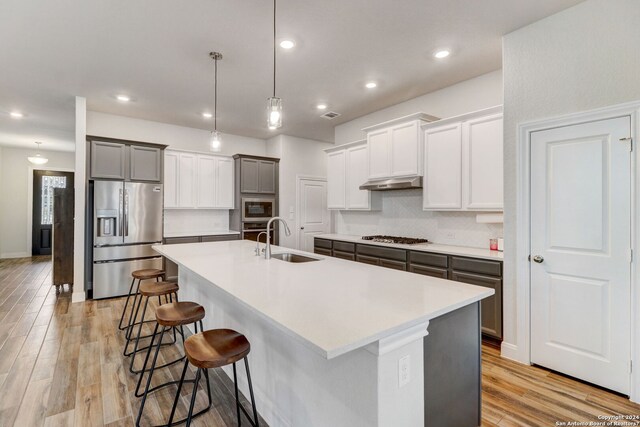 kitchen with a center island with sink, a kitchen bar, appliances with stainless steel finishes, and sink