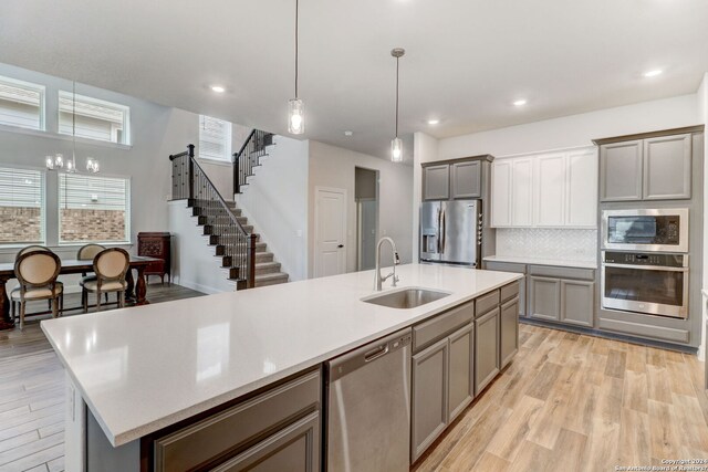 kitchen featuring a notable chandelier, appliances with stainless steel finishes, hanging light fixtures, and an island with sink