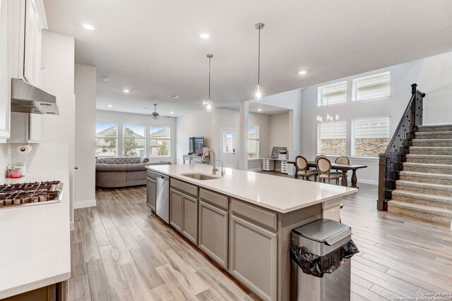 kitchen featuring wall chimney exhaust hood, light hardwood / wood-style floors, ceiling fan, and sink