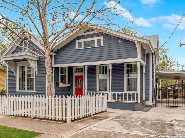 view of front of property with a fenced front yard, a porch, a gate, a carport, and driveway