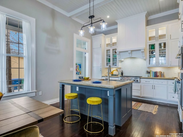 kitchen featuring dark hardwood / wood-style floors, pendant lighting, backsplash, a kitchen bar, and white cabinetry