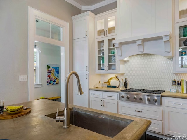 kitchen with sink, white cabinets, custom range hood, stainless steel gas stovetop, and tasteful backsplash