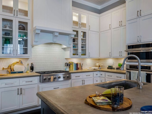 kitchen with white cabinets, crown molding, stainless steel appliances, custom exhaust hood, and backsplash