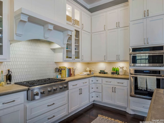 kitchen with dark hardwood / wood-style floors, crown molding, white cabinets, stainless steel appliances, and tasteful backsplash