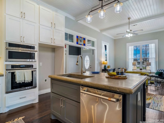 kitchen with ceiling fan, appliances with stainless steel finishes, sink, white cabinets, and beam ceiling