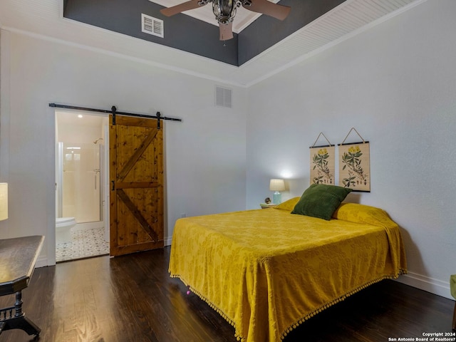 bedroom with a barn door, connected bathroom, ceiling fan, and dark hardwood / wood-style floors