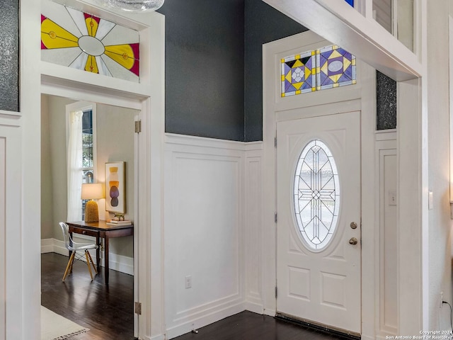 entrance foyer with dark wood-style flooring, wainscoting, and a decorative wall