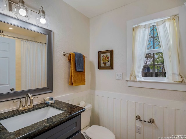 bathroom featuring toilet, vanity, and wainscoting