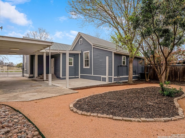 back of house with an attached carport, metal roof, fence, and entry steps