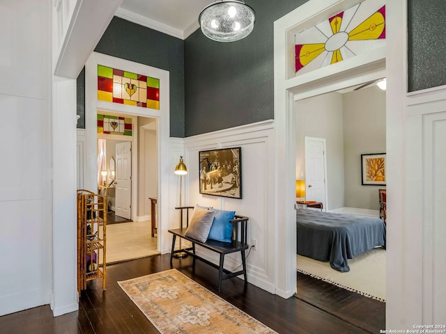 corridor featuring crown molding, dark wood-style flooring, wainscoting, and a decorative wall