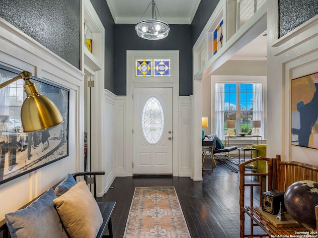 entryway with an inviting chandelier, crown molding, dark hardwood / wood-style floors, and a high ceiling