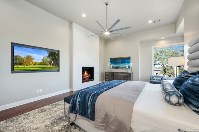 bedroom featuring ceiling fan, a fireplace, and hardwood / wood-style flooring