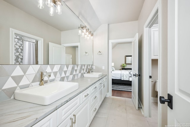 bathroom with backsplash, a chandelier, hardwood / wood-style floors, and double vanity