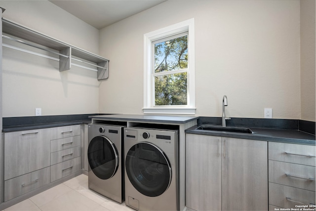 laundry area featuring light tile patterned flooring, cabinets, washing machine and dryer, and sink