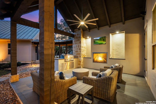 patio terrace at dusk featuring area for grilling, an outdoor hangout area, an outdoor kitchen, and ceiling fan